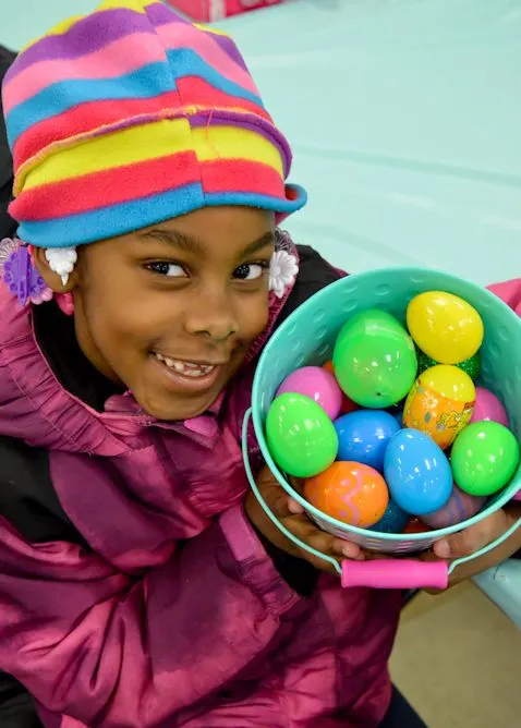 A smiling girl holding a basket of colorful plastic eggs at the Spring Festival